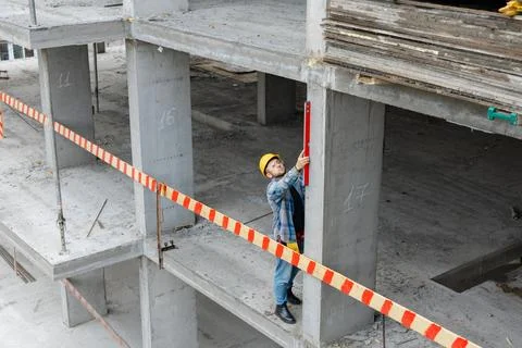 Construction worker checking vertical concrete pillar with spirit level 스톡 사진