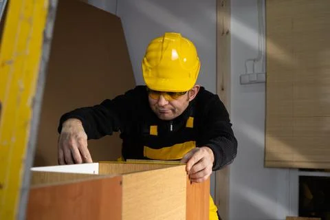 A construction worker checks a pull-out cupboard at the top with a tape measure Foto stock