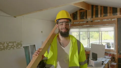 A Construction Worker is Cheerfully Smiling While Holding Lumber in a Recently Stock Footage 305817310