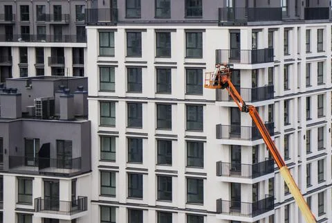 Construction worker in a cherry picker basket repairing an apartment facade.. Foto stock