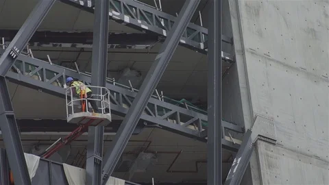 Construction worker on a cherry picker inspecting building Stock Footage 93202477