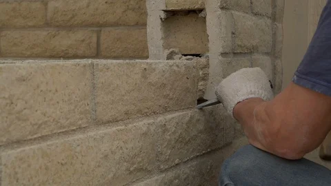 A construction worker chiseling brick out of a wall Stock Footage 100933642