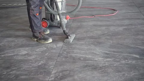 Construction worker cleaning dust with vacuum cleaner after laying floor tile 스톡 사진