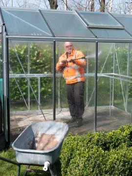 Construction worker cleaning filth with high pressure cleaner from a glass Stock Photos