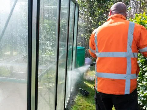 Construction worker cleaning filth with high pressure cleaner from a glass Stock Photos