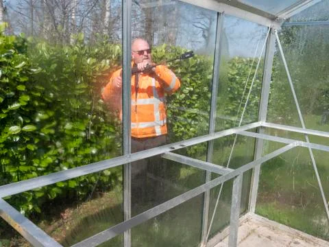 Construction worker cleaning filth with high pressure cleaner from a glass Stock Photos