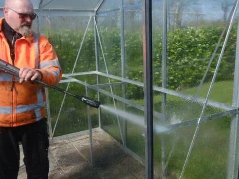 Construction worker cleaning filth with high pressure cleaner from a glass Stock Photos