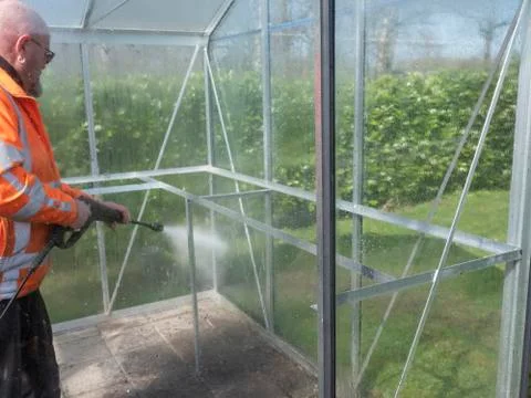 Construction worker cleaning filth with high pressure cleaner from a glass Stock Photos