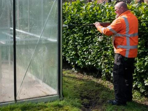 Construction worker cleaning filth with high pressure cleaner from a glass Stock Photos