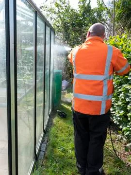 Construction worker cleaning filth with high pressure cleaner from a glass Stock Photos