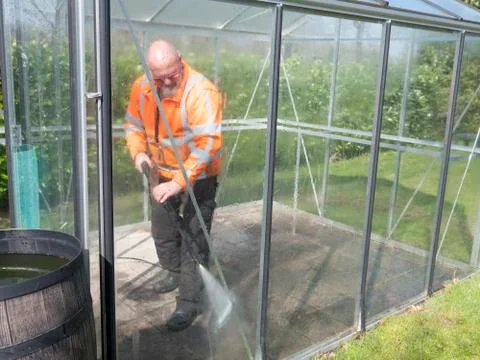 Construction worker cleaning filth with high pressure cleaner from a glass Stock Photos