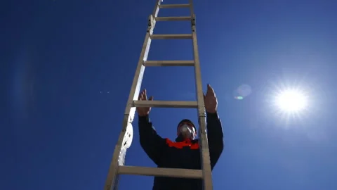 Construction worker climbing up ladder against blue sky and the sun Stock Footage 108545000