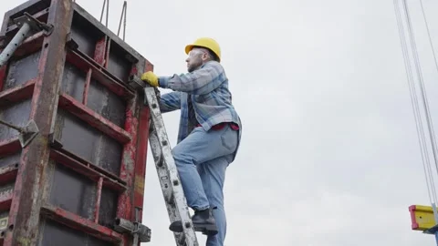 Construction worker climbing ladder on building site Video stock 337470186