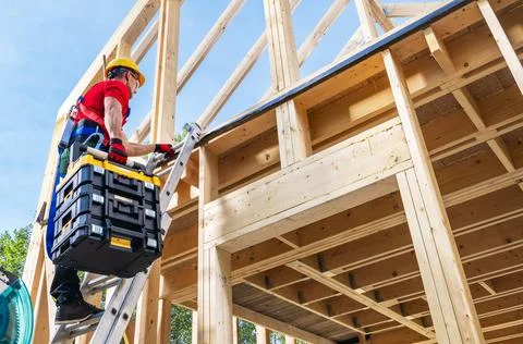 Construction worker climbing a ladder on a building site during the day Fotos Stock