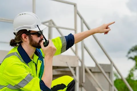 Construction worker communicates on radio while monitoring site activities .. Stock Photos