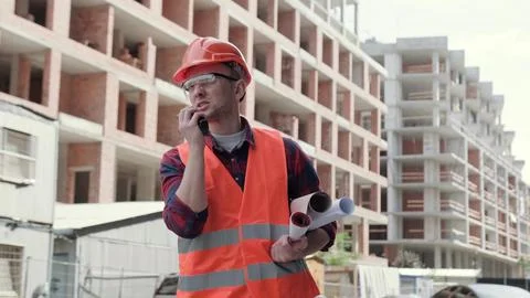 Construction worker communicating over two-way radio on development site 스톡 사진