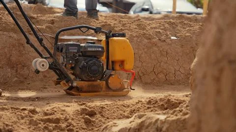 Construction worker compacting soil at building site Stock Photos