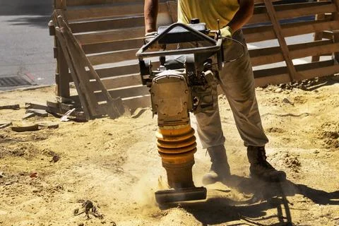 Construction worker compacting soil in house foundation using compactor. Wo.. Stock Photos