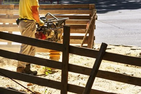 Construction worker compacting soil in house foundation using compactor. Wo.. Stock Photos