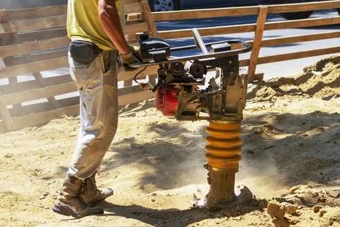 Construction worker compacting soil in house foundation using compactor. Wo.. Stock Photos