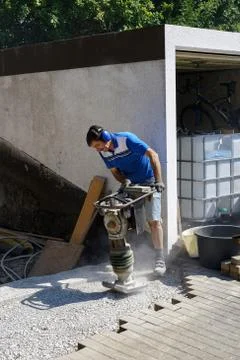 Construction worker compacting soil using compactor. Work with tamping machin Stock Photos
