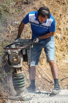 Construction worker compacting soil using compactor. Work with tamping machine Stock Photos