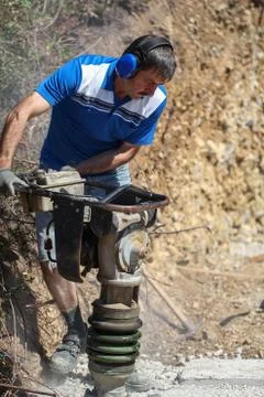 Construction worker compacting soil using compactor. Work with tamping machine Stock Photos