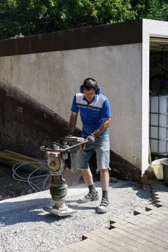 Construction worker compacting soil using compactor. Work with tamping machin Stock Photos