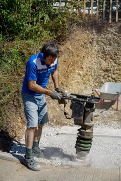 Construction worker compacting soil using compactor. Work with tamping machin Stock Photos