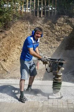 Construction worker compacting soil using compactor. Work with tamping machin Stock Photos