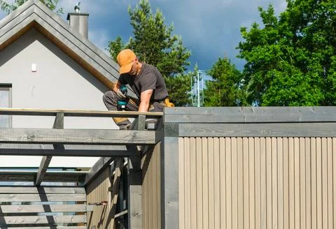 Construction Worker Completing Roof Work on a Residential Building in Sunny.. Stock Photos