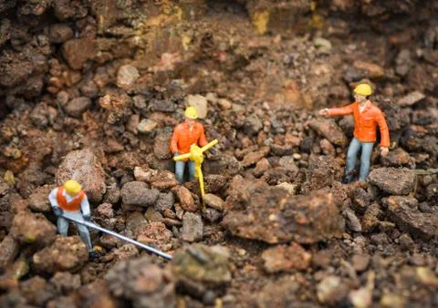 Construction worker concept / figurines working digging ground soil with team Stock Photos