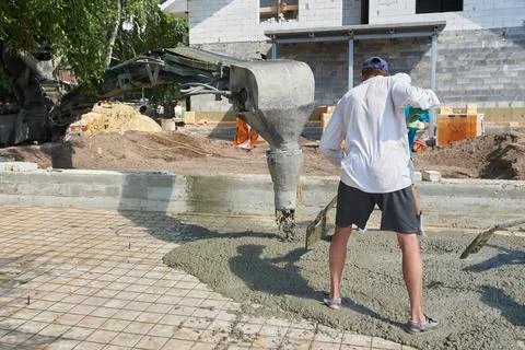 Construction worker in the concrete at the construction site during flooring Foto stock