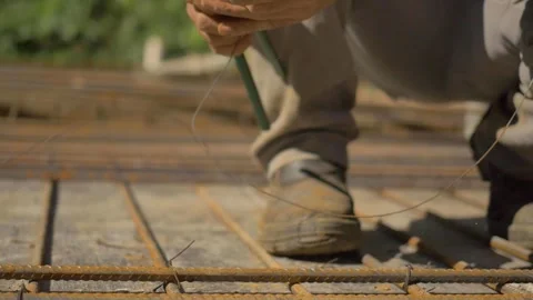 Construction worker connecting rebar to rebar mesh as part of a slab build up Stock Footage 255684380