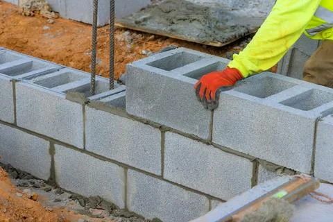 Construction worker constructing concrete block wall at building site during Foto stock