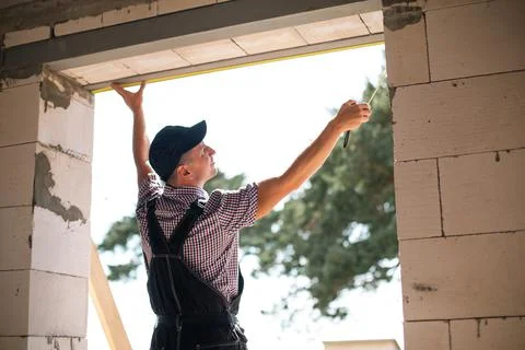 Construction worker at construction site measures the length of window openin Stockfoto's