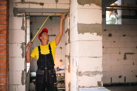 Construction worker at construction site measures the length of window openin Stock-Fotos