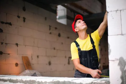 Construction worker at construction site measures the length of window openin Foto stock