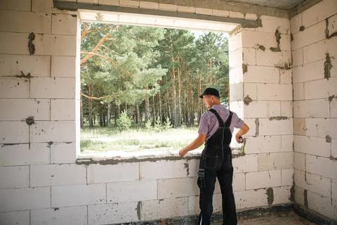 Construction worker at construction site measures the length of window openin Stock-Fotos