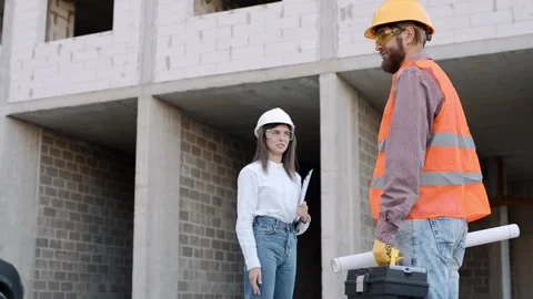 Construction worker consults with engineer on building site with plans Stock Footage 295956363