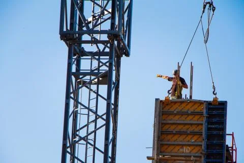 A construction worker controls the crane movement when assembling building bl Foto stock