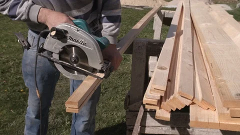 Construction worker cuts boards with circular saw Stock Footage 99888818