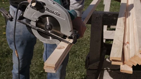 Construction worker cuts boards with circular saw Stock Footage 99889830