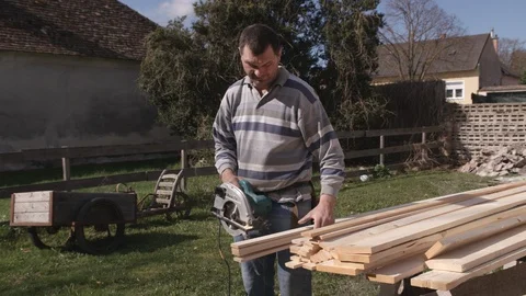 Construction worker cuts boards with circular saw Stock Footage 99890128