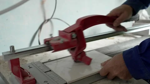 Construction worker cuts ceramic tile using tile cutting hand machine Stock Footage 285942451