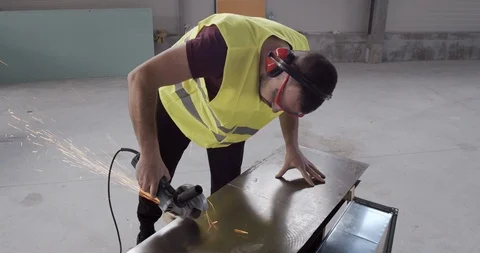 A construction worker cuts a metal with an angular grinder. Stock Footage 126999205