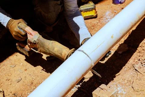 Construction worker cuts pipe on work site using power tool Stock Photos