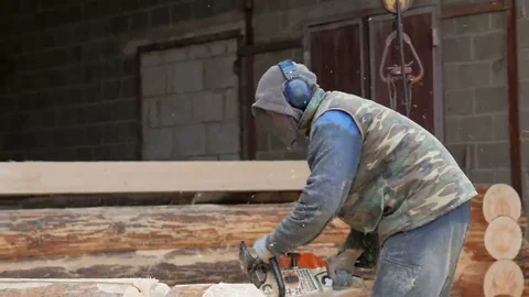 Construction worker cuts wood chainsaw for future home. Protective mask and Stock Footage 69072744