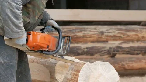 Construction worker cuts wood chainsaw for future home. Protective mask and Stock Footage 69073533