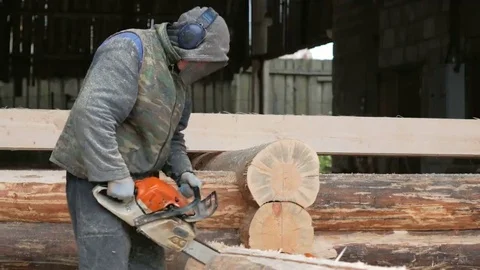 Construction worker cuts wood chainsaw for future home. Protective mask and Stock Footage 69074946